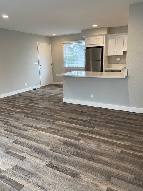 A kitchen with a refrigerator, cabinets, and a countertop.